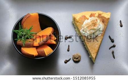 A slice of homemade sweet pumpkin pie and pumpkin pieces on silver background. Top view