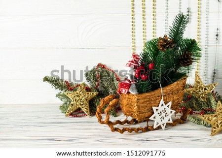 Christmas decorations with sled, penguin, pinecones, green spuce tree branches and gold decorative stars. Greetings card with copyspace for your text