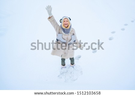 Beautiful woman walking in winter park and feeling wonderful. Happy winter fun woman. Model wearing stylish knitted winter hat and gloves