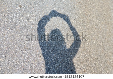 Shadow of a woman while taking a selfie, on an asphalt background