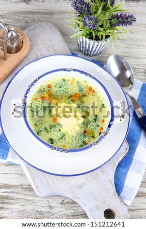 Soup in plate on napkin on wooden board on table