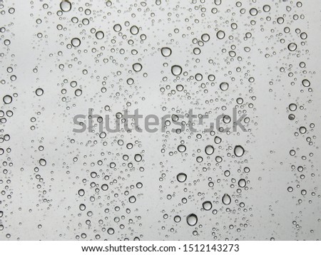 Raindrops on a transparent glass on a light background.        