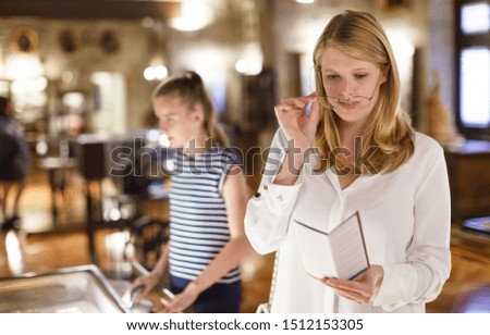Young woman  looking at guidebook in museum of arts, girl on background