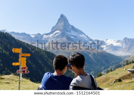 Two tourists taking a picture with the smart phone of the mountain Matterhorn in Zermatt, Valais, Switzerland