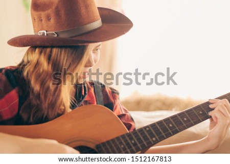 Music Concepts. Asian Caucasian girl in countryside playing guitar. Asian women relaxing with music. Asian women have a happy lifestyle.