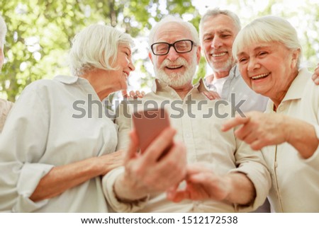 Smiling old people watching funny video on smartphone stock photo