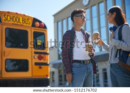 Smiling students holding coffee outdoors stock photo