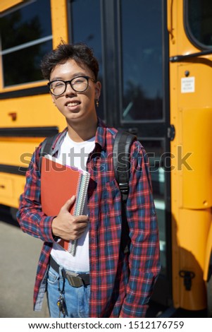 Smiling young guy standing near school bus stock photo