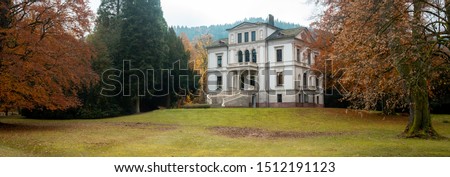 A panoramic view of a typical huge film mansion and its garden, autumnal manor house aesthetic. The location is the Black Forest region, in Germany. Royalty-Free Stock Photo #1512191123