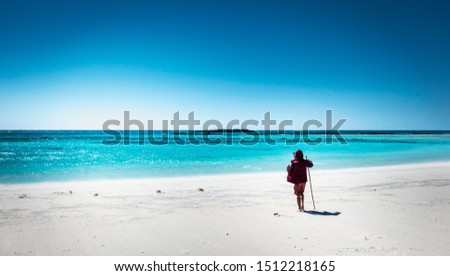 Rear view of boy standing on seashore overlooking turquoise sea water