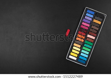 Colourful chalk palette on empty school blackboard with copy space