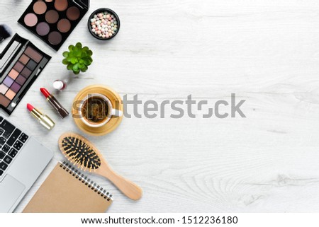Female cosmetics on white office desk. Laptop, notepad, Lipstick, powder, comb, women's jewelry. Top view. Free space for your text. Flat lay.