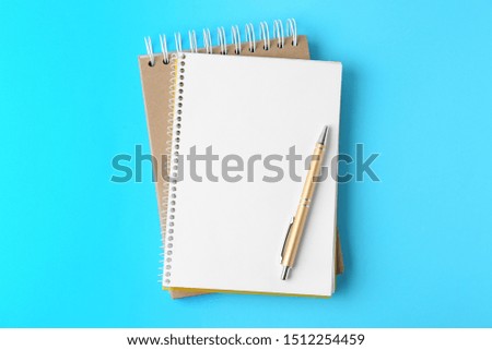 Notebooks and pen on light blue background, top view
