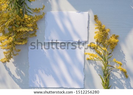 Stylish branding mockup to display your artworks. Mock up on wooden table background. Flat lay top view. Blank greeting card. Feminine wedding stationery, desktop scene with yellow flowers.