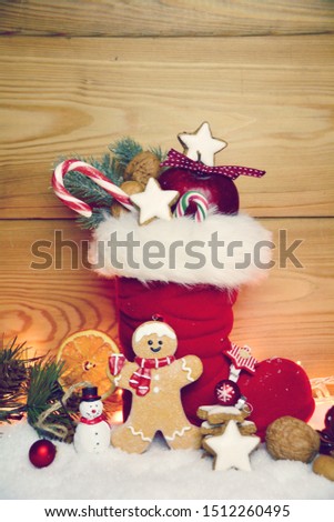 Stuffed Santa Claus boot with sweets and gingerbread man in the snow.Cute rustic background