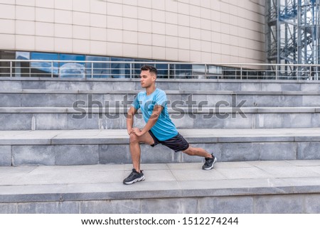 A male athlete makes lunges, training legs, in summer in city, in morning in fresh air. Youth lifestyle, active modern guy athlete, free space for text motivation.