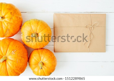 Autumn orange pumpkins with gift in brown paper package tied up with strings on old white wooden background Thanksgiving and Halloween concept. Top view. Copy space for text and design