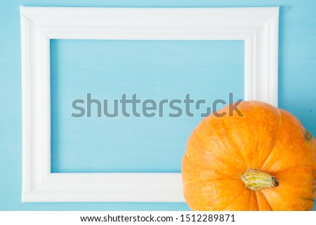 Thanksgiving season still life with orange pumpkins and with white frame for picture over rustic blue wood background Thanksgiving and Halloween concept. Copy space for text and design