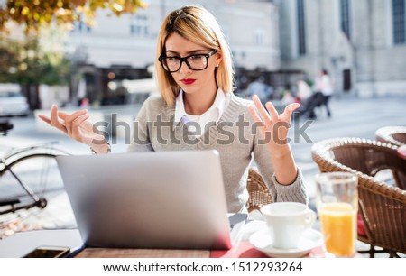 Young businesswoman sitting in a cafe drinking coffee and working with laptop, making a notes. Business, education, lifestyle concept