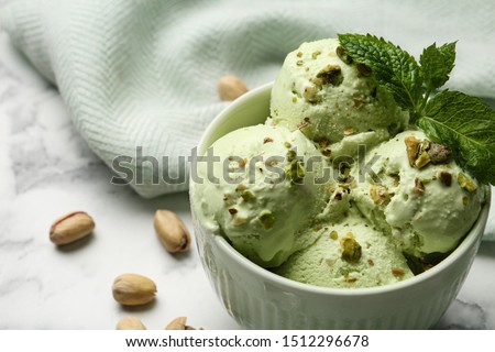 Tasty pistachio ice cream with mint on marble table, closeup view