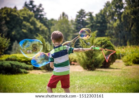 Little boy playing with his soap bubbles toy in the park. Child activity. Springtime concept.
