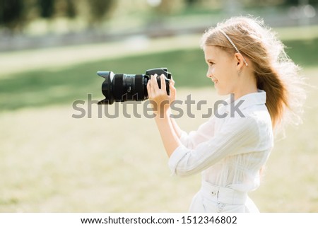 young girl takes camera outdoors , child with a camera