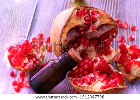 Pomegranate seed oil in bottle and pomegranate on wooden background