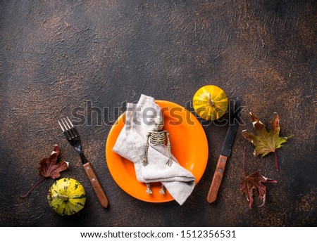 Halloween table setting with pumpkin and skeleton
