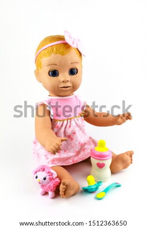 Cute little plastic baby doll isolated on white background. Caucasian newborn baby doll are sitting.