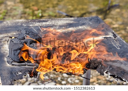At the campsite of tourists, a camera burns, which ignites with other property as a result of a forest fire. The flame destroys the photo equipment of a tourist photographer.