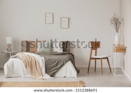 Stylish chair next to warm king size bed in scandinavian bedroom Royalty-Free Stock Photo #1512388691