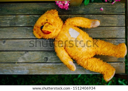 Old vintage teddy bear with the patch on the heart. Forgotten toy. Solitude concept. Children loneliness concept. Heart surgery concept. Broken heart concept. 