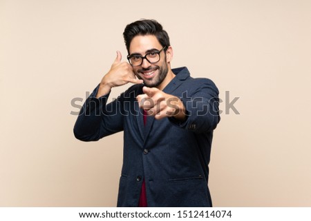Handsome young man over isolated background making phone gesture and pointing front