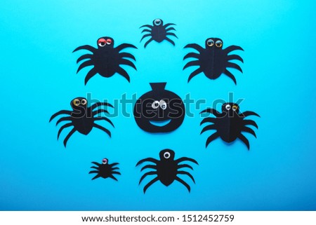 Funny paper spiders and pumpkin with eyes on a blue background. Halloween decorations concept. Happy Halloween day. Flat lay, top view. Party invitation, celebration
