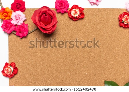 Frame made of rose flowers on cork board  background. Top view with copy space. Flat lay design concept.