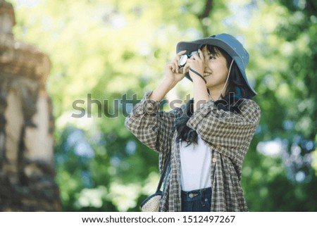 Young Asian traveler woman taking photo by her camera while traveling around Thai ancient temple on holidays vacation.