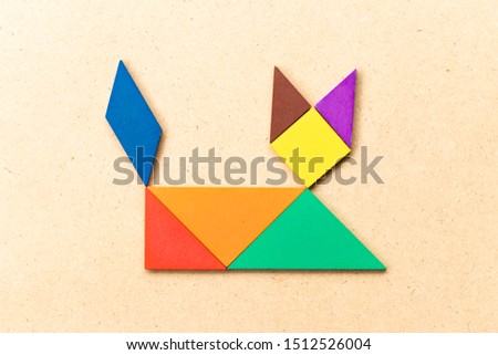 Color tangram puzzle in lying down cat shape on wood background