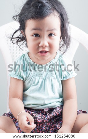 Portrait of little girl over grey wall background