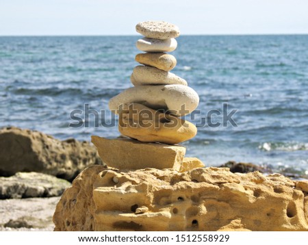 Simple poise pebbles stack, rock zen sculpture, a stone tower. Beach sand stone zen cairn. A stone pyramid on sea shore.