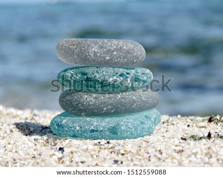 Sea glass pyramid on beach sand with blurred seascape background. Beachcombing, beach walk. Harmony and balance concept. Royalty-Free Stock Photo #1512559088