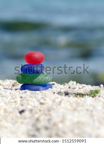 Seaglass zen cairn on blurred sea background. A sea glass pyramid on sea shore. Poise glass stack. Harmony with nature. Royalty-Free Stock Photo #1512559091