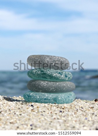 Sea glass on beach sand with seascape background. Beachcombing. Harmony and balance concept. Vertical composition. Royalty-Free Stock Photo #1512559094