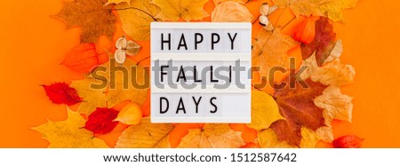 Autumn flat lay composition with dry leaves wreath frame and lightbox message Happy fallidays on bold orange color background. Creative autumn thanksgiving fall halloween concept. Top view, copy space