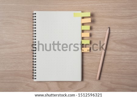 Notepad or notebook with sticky notes and pencil on brown wood table.using for education, business background. Take note on book with paper and concept, copy space for your text