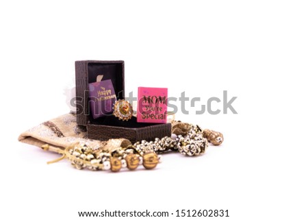 Mom's anniversary concept. Golden ring in a lather gift box with handmade pouch and mom you're special card on white background