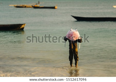 A fisherman is carrying a skate fish/stringray at Nungwi Beach / Zanzibar Royalty-Free Stock Photo #1512617096