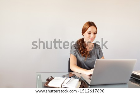Portrait beautiful smart professional businesswoman typing on laptop computer with white wall space, home office interior. Intellectual female confident at work, business technology people lifestyle.