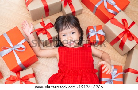 Portrait of little cute asian girl lying and playing on the floor with gift boxes, Christmas boxing day concept. asian small girl opening Christmas presents. Holiday toddler lifestyle concept