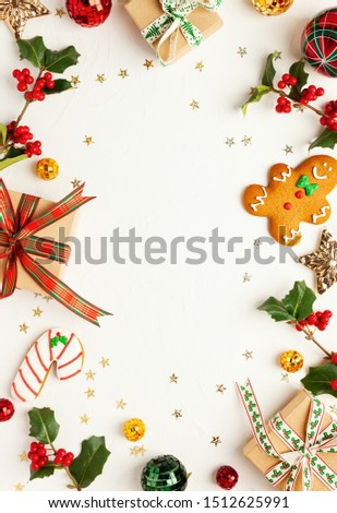 Christmas background with gingerbread cookies, gift boxes and branches of holly with red berries on white. Winter festive nature concept. Flat lay, copy space.