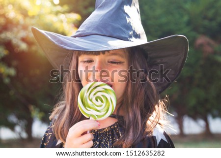 Girl dressed as a witch eating candy. happy Halloween